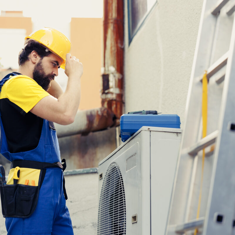 Technicien travaillant sur un groupe extérieur de climatisation